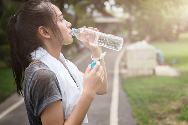 girl drinking water while jogging